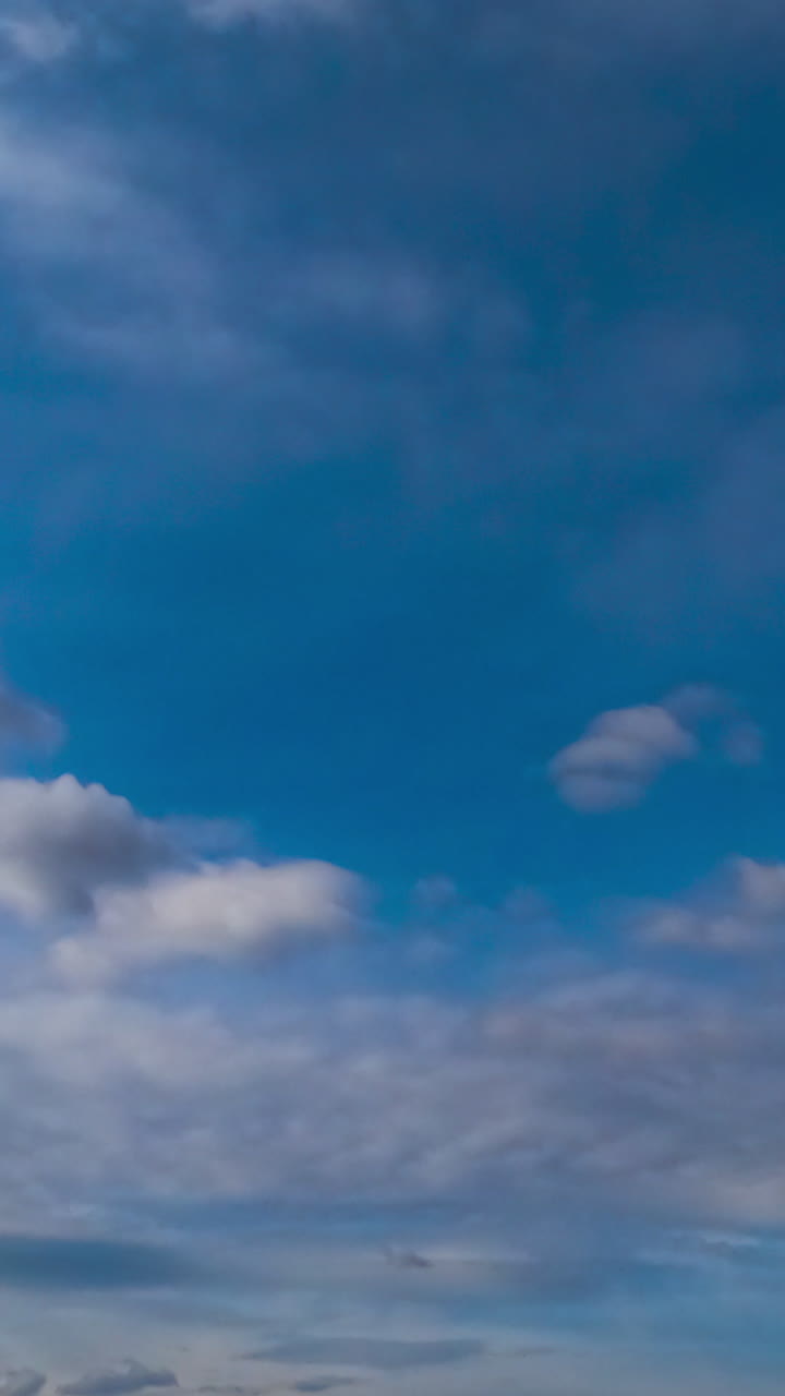 Light clouds transforming into heavy grey dramatic cloudscape. Low angle view. Timelapse. Vertical video