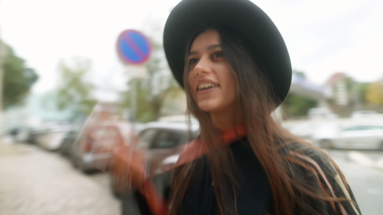 Jeune femme heureuse marchant dans une rue de la ville et filmant avec son téléphone