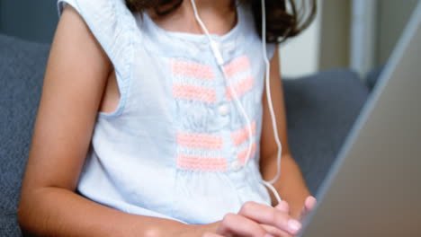 girl with headphones using laptop in living room