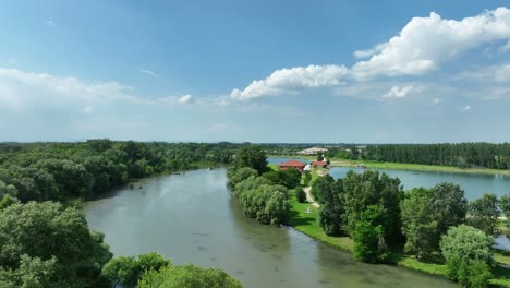 aerial drone footage ascends above the small danube river, unveiling gravel pits, pristine emerald lakes, and picturesque fields below