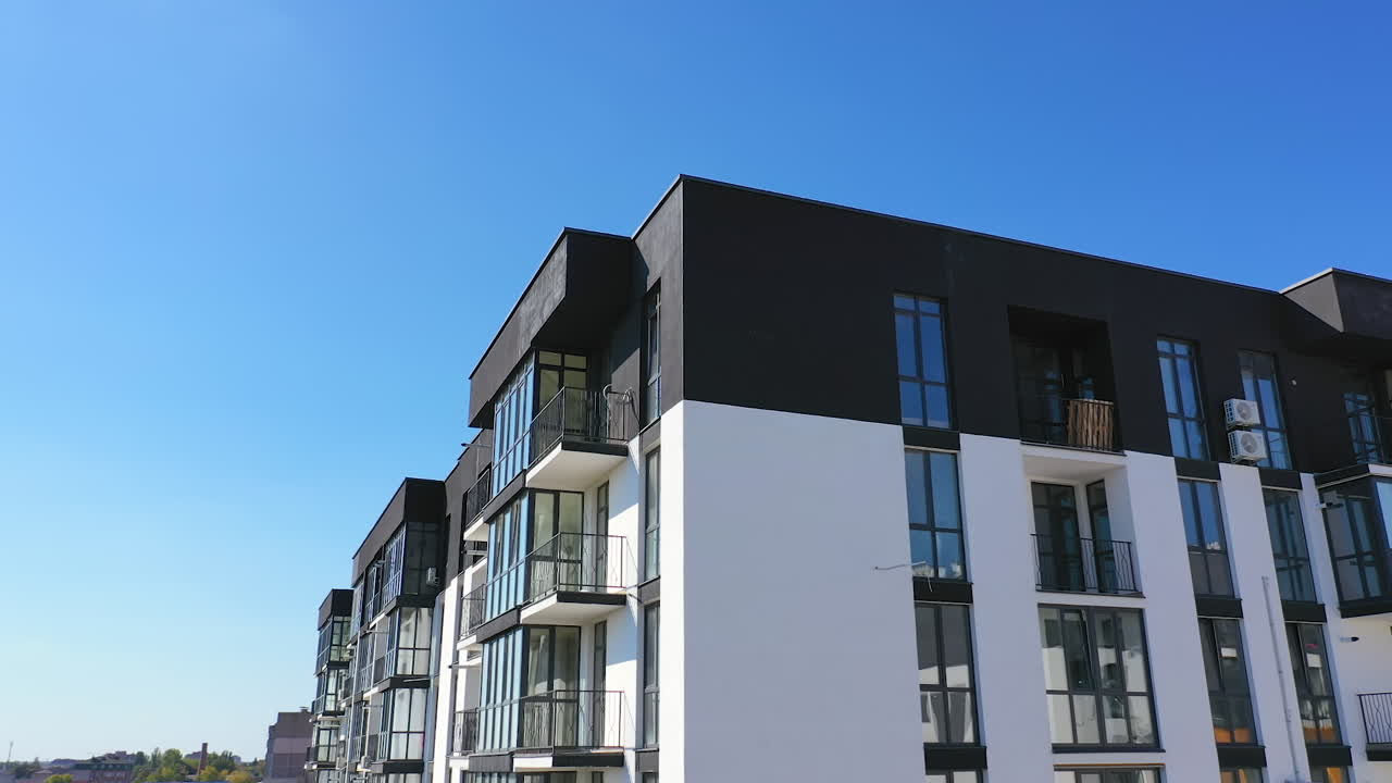 Beautiful design of multistorey building. New apartment with balconies against blue sky. Exterior of residential building.