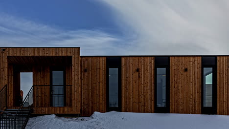 a view of a modular wooden cabin set against a snowy landscape - timelapse