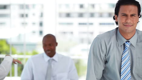 Businessman-looking-at-the-camera-while-his-colleagues-are-talking