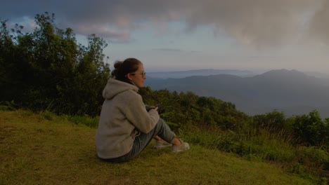 woman admiring a panoramic mountain view at sunset