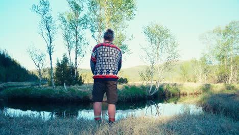 rear of a man fishing on a small pond