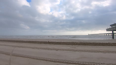 pov of a slowly driving vehicle on the beach past a fishing pier on north padre island national near corpus christi texas usa as storm approaches