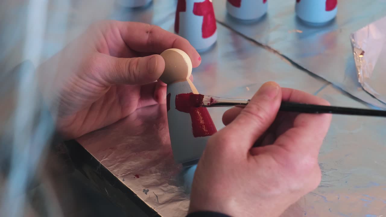 vista en primera persona del artista pintando muñecas hechas a mano con pintura roja, de cerca