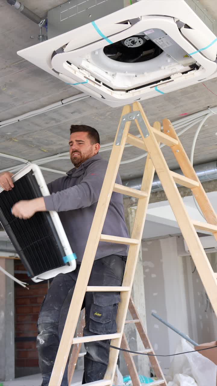 Man Installing Air Conditioning Unit on Ceiling at Construction Site