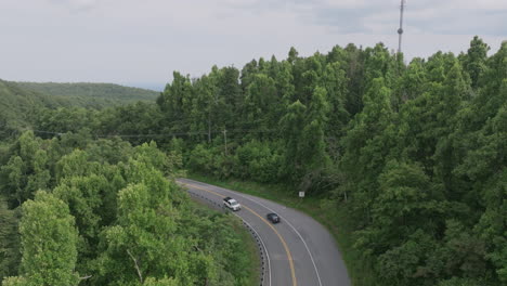 close and fast aerial footage of a mountainous curvy road amongst the hazy green mountains and valleys of southern virginia