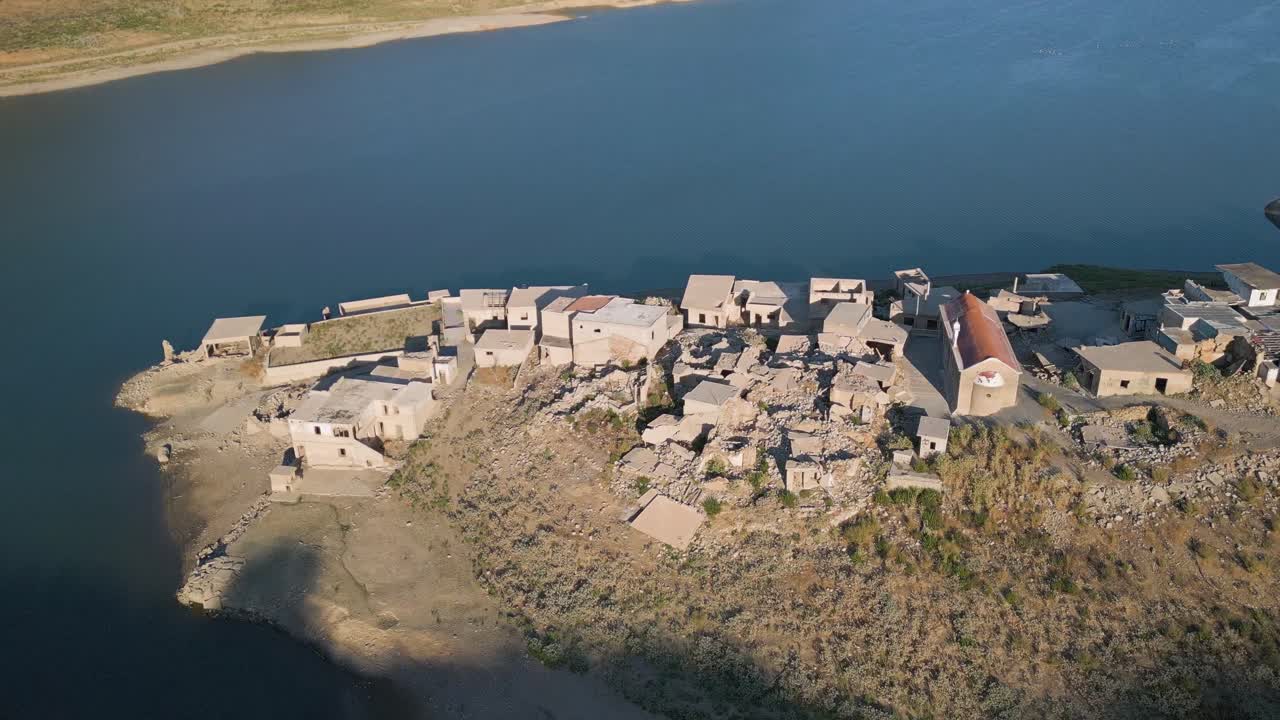 A stunning aerial reveal of Aposelemis Lake and dam, captured from the partially submerged village of Sfendili in Crete, showcasing water reflections, heritage, and nature