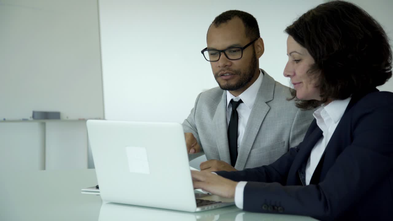 Manager sicuri di sé che indossano un abito formale e usano il laptop.