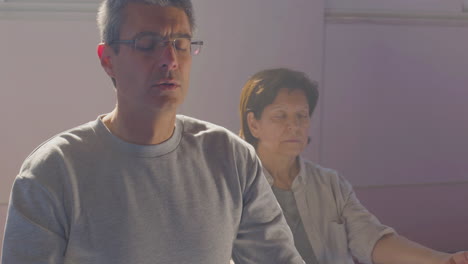 senior man and woman meditating in lotus position