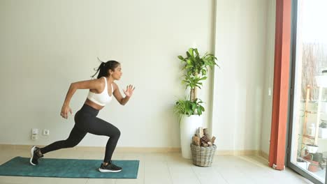 Ethnic-sportswoman-jumping-during-workout-in-room