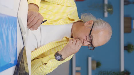 Vertical-video-of-Home-office-worker-old-man-focused-on-thinking.