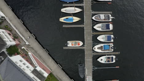 speedboats and sailboats anchored at the wooden jetty by the norwegian coast in arendal, norway