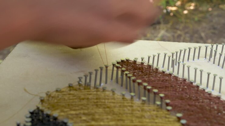 L'artista di string art sta dando gli ultimi ritocchi all'opera e riempiendo le aree rimanenti con fili lucidi