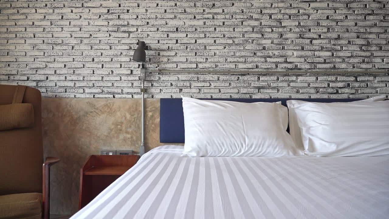 호텔 침대 발치에서 벽돌 벽 배경으로 천천히 아래로 기울어지는 화면