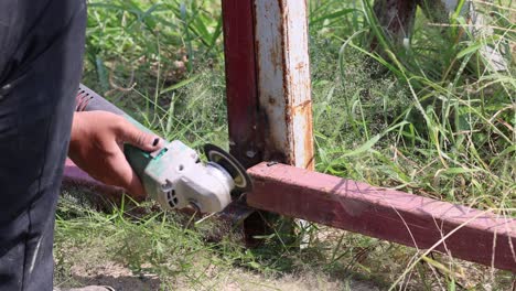 persona que utiliza una molienda angular para cortar una barra de metal.