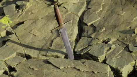 espada incrustada en el suelo rocoso durante el día en un paisaje sereno