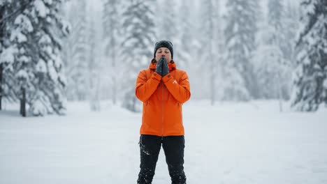 a person in an orange jacket enjoys the tranquility of a snowy landscape, embracing the peacefulness of winter in a serene forest setting