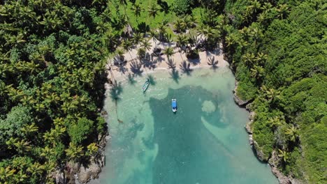 Ascending-aerial-top-down-of-private-sandy-beach-with-boats-and-palm-trees