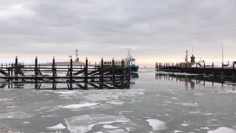 ship entering a harbor full of ice on a cloudy winter day