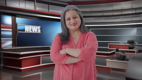 feliz periodista india de alto rango de pie con las manos cruzadas