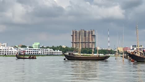 dolly shot along the buriganga river with wooden boats paddling passengers across the city