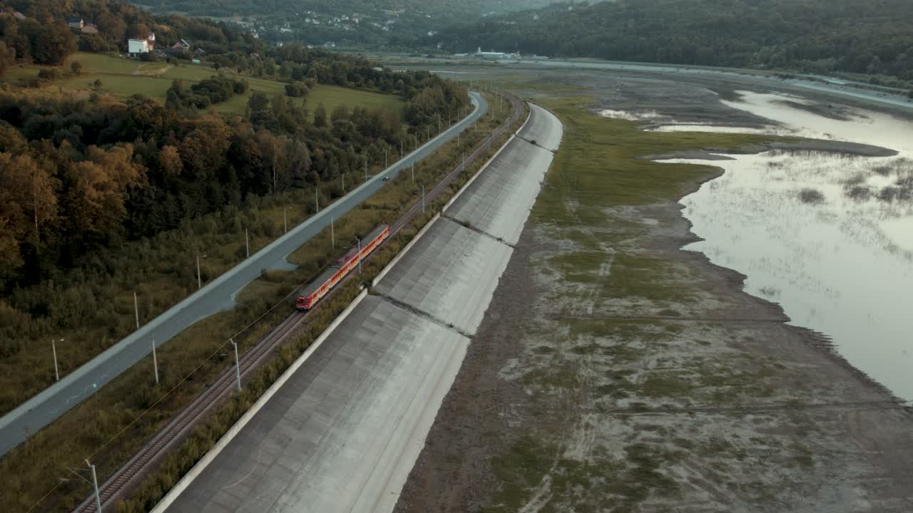Passenger train moving along dry lake in stunning sunset scenery (4k drone shot)