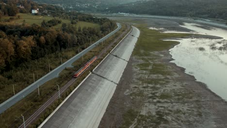 passenger train moving along dry lake in stunning sunset scenery (4k drone shot)