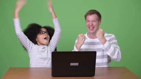 una joven africana y un joven escandinavo usando una computadora portátil juntos
