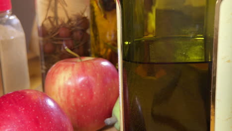 close up of olive oil with apples and herb infused vinegar on counter