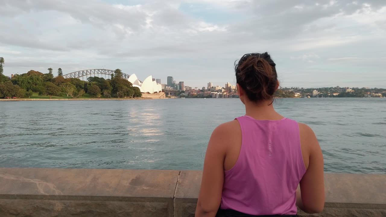 잘 알려진 랜드마크에 놀란 소수 민족 여성의 백뷰 - 호주 배경에 하버 브리지가 있는 시드니 오페라 하우스