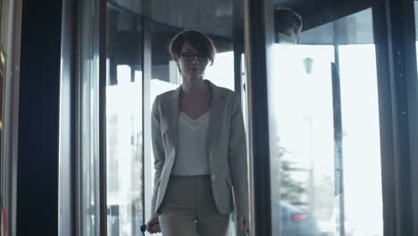 businesswoman and a businessman in elegant clothes enter the hall of a hotel with suitcases