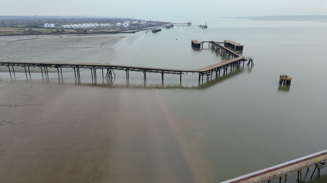 Droneoptagelse i filmisk stil over River Thames ved Canvey Island, UK, der fremhæver brændstofterminalens rørledninger, lagerfaciliteter og maritime læsseoperationer