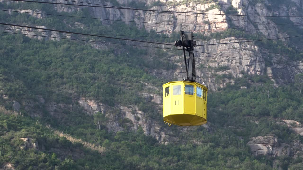 teleférico amarillo deslizándose por el lado de la montaña cubierto de arbustos verdes