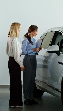 vendedor de automóviles mostrando el vehículo al cliente en el concesionario