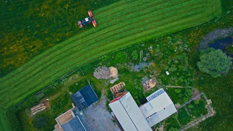 bird's eye view of mower working in the farm field - drone shot
