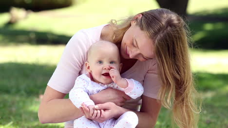 madre feliz sosteniendo a su niña en el parque