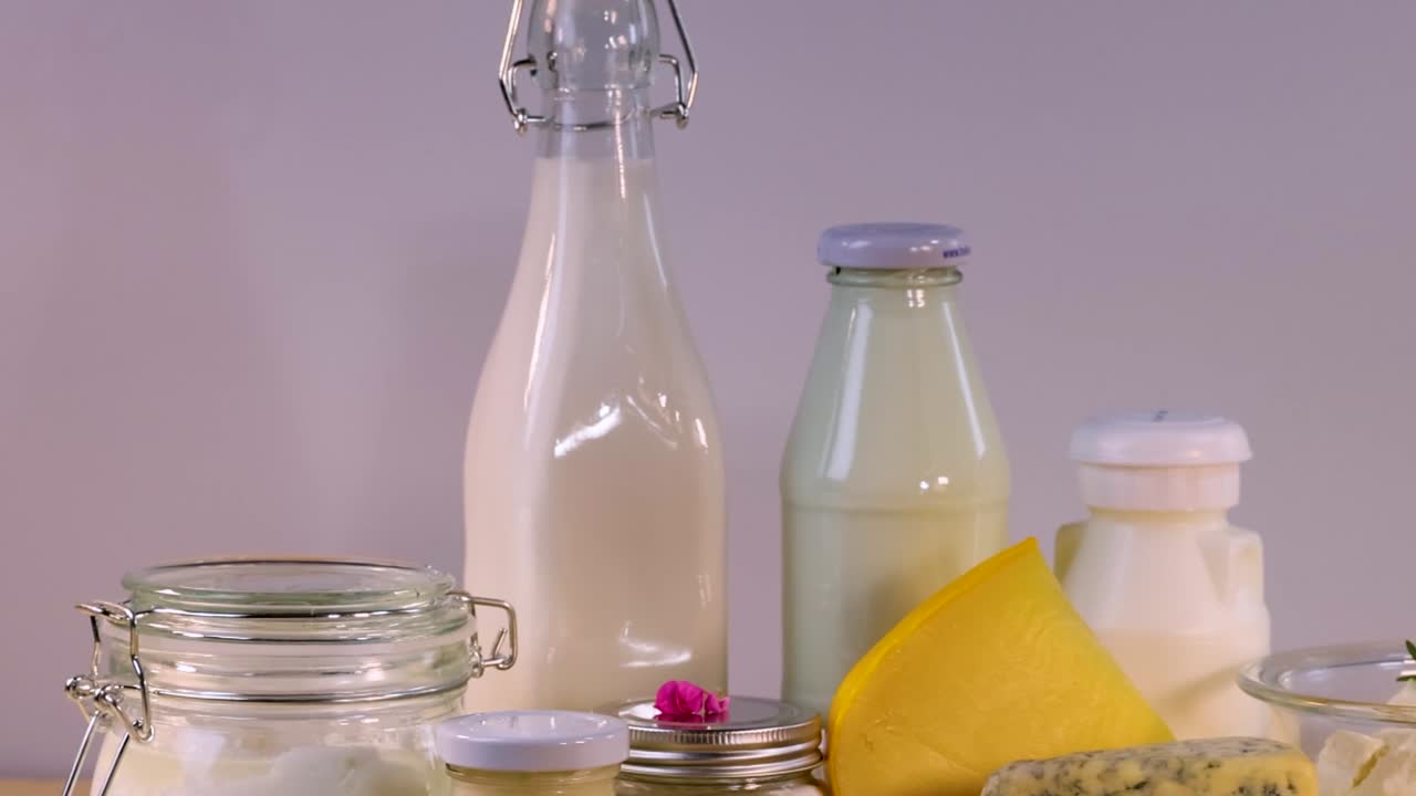 A selection of milk bottles and jars arranged with a yellow cloth and small pink flower.