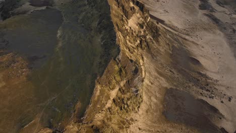 drone shot of a steep cliff face in búrfell, iceland, showcasing rugged textures and contrasting light over the rocky terrain