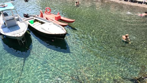 boats docked, people swimming in clear water