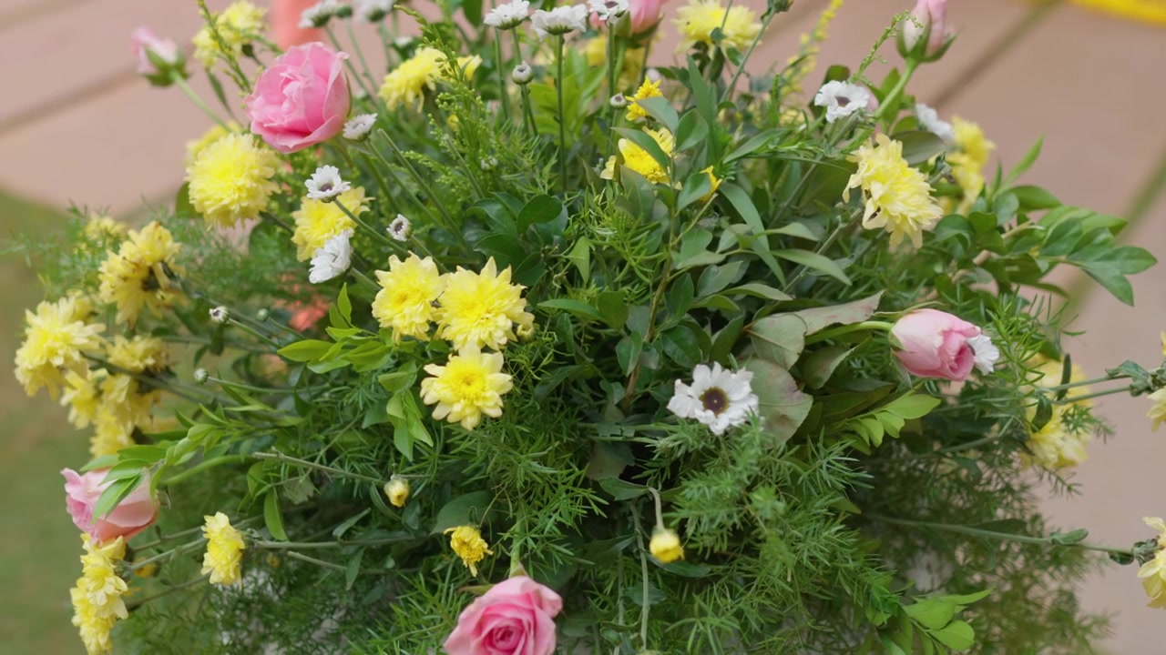 Nærbillede af frisk blomsteropsætning med lyserøde og gule blomster ved udendørs arrangement