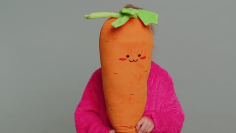 young preteen child girl kid playing hide and seek, peek a boo, hiding behind big plush carrot toy