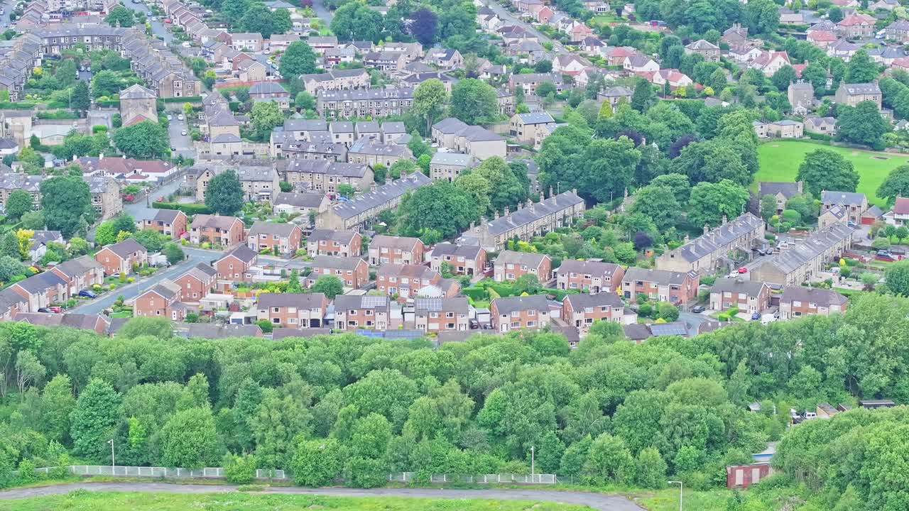 This aerial view captures a dense residential area with numerous houses, lush greenery, and tree cover. The well-organized suburban neighbourhood showcases a blend of architecture and nature