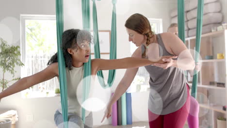 animación de puntos de luz sobre diversas instructoras y adolescentes practicando yoga aéreo