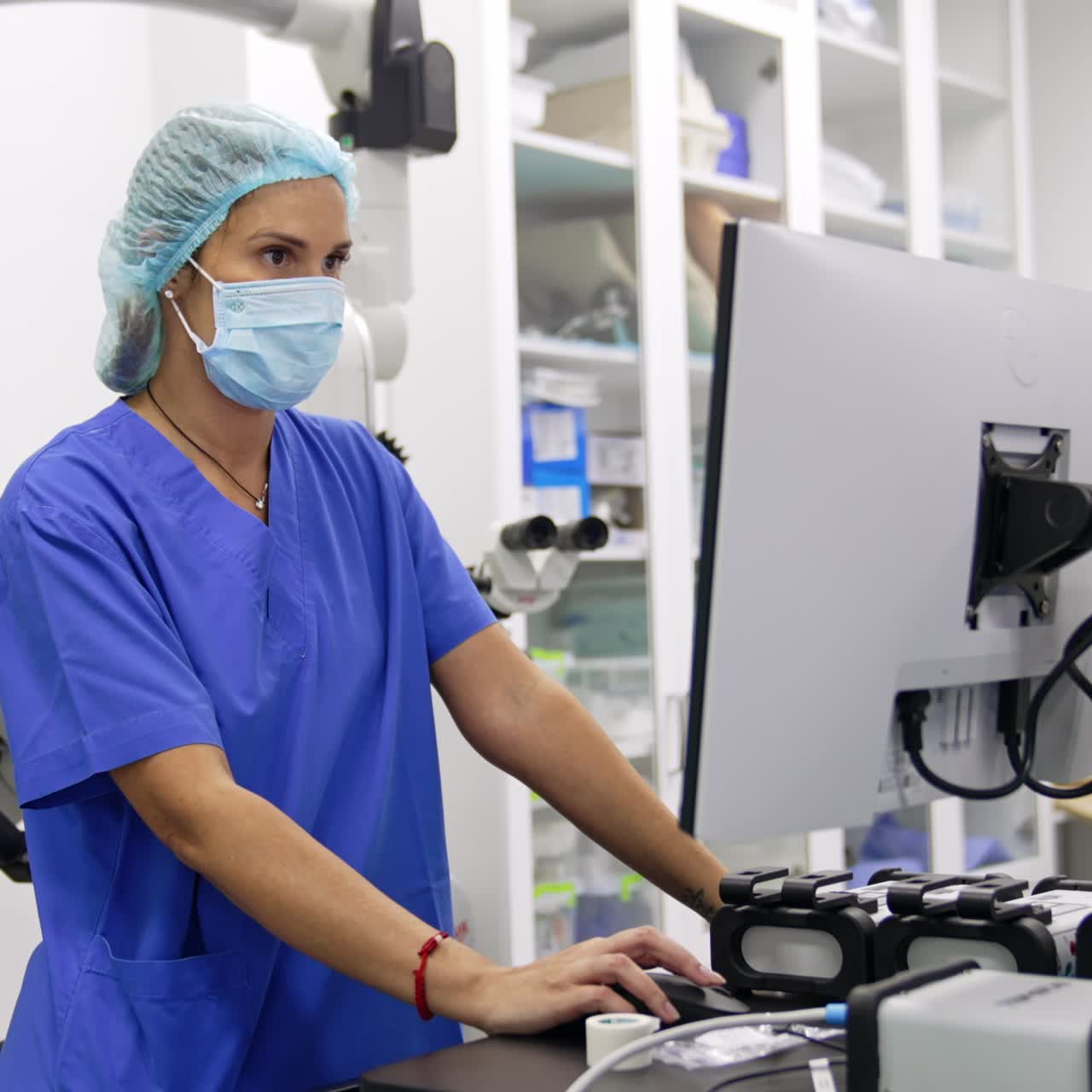 Una médica se encuentra de pie frente a la pantalla de un ordenador. Una doctora concentrada realiza neuromonitorización en un hospital.