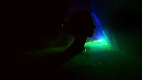 imagen de una niña en un fondo claro de diferentes colores moviéndose en la oscuridad. el humo llena el triángulo con la cabeza de la niña. proyector.