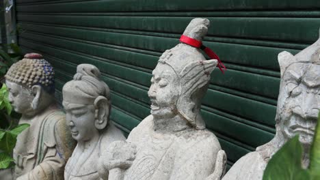 religious buddhist stone statues are seen in front o a closed antique shop