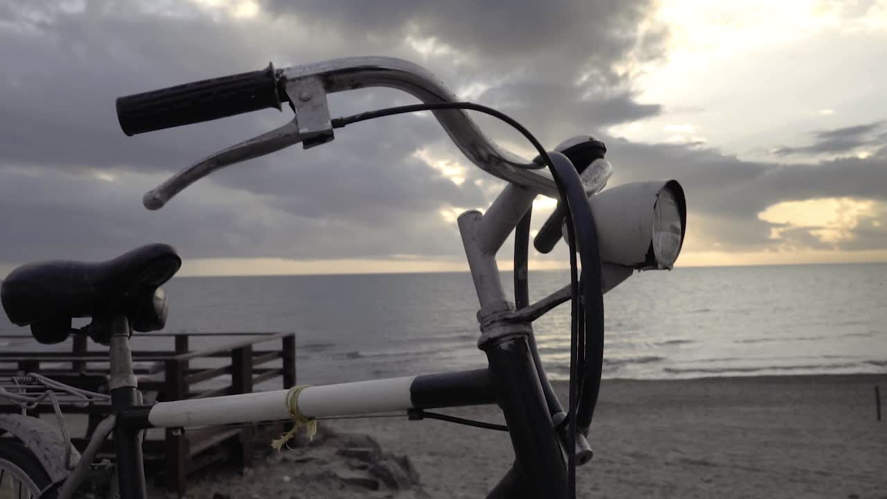 Vintage '80s touring bicycle by the sea with sunset in the back SLOW MOTION 120 FPS - Orbiting front shot